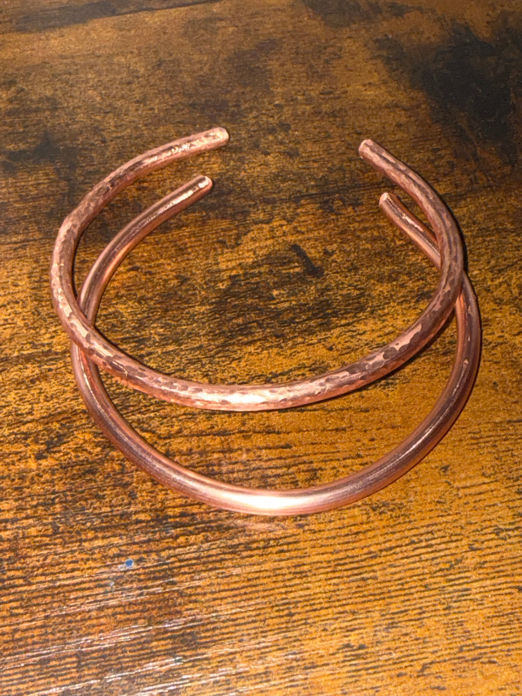 2 copper cuffs on wooden surface